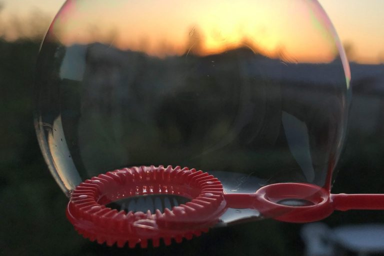 Bulle de savon refletant un coucher de soleil, avec un contour rouge.