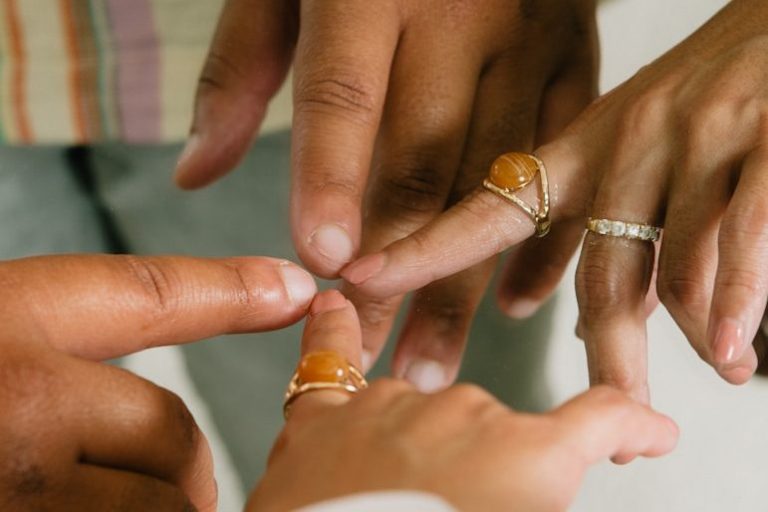 Trois mains avec des bagues touchant délicatement les doigts.