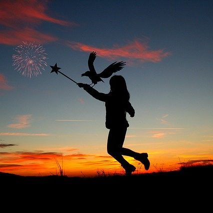 Silhouette d'une fille avec une baguette magique et un oiseau, au coucher de soleil.